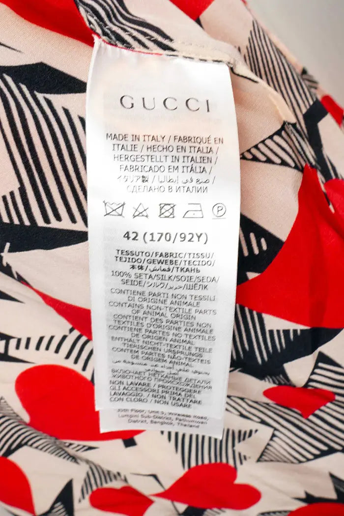 Blusa suelta Gucci de seda con corazones rojos y negros entrelazados, artículo seminuevo, zoom en la etiqueta de composición