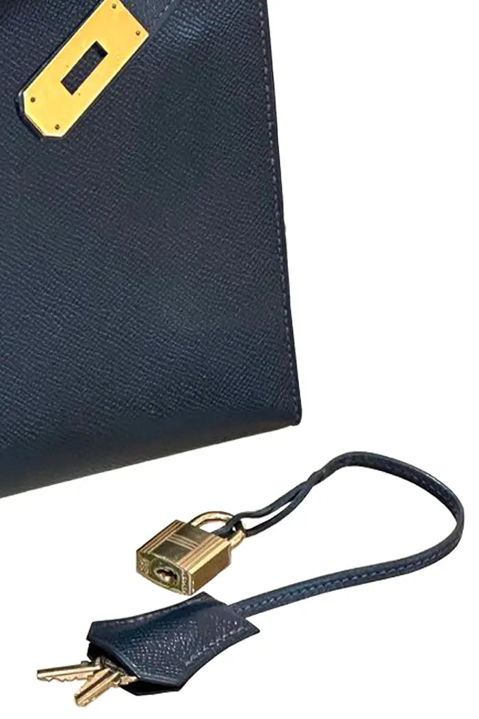 Zoom auf das Vorhängeschloss und das Glöckchen der gebrauchten Hermès Kelly 28 Tasche aus nachtblauem Epsom-Leder mit vergoldeten Metallbeschlägen. Zertifiziert authentisch.