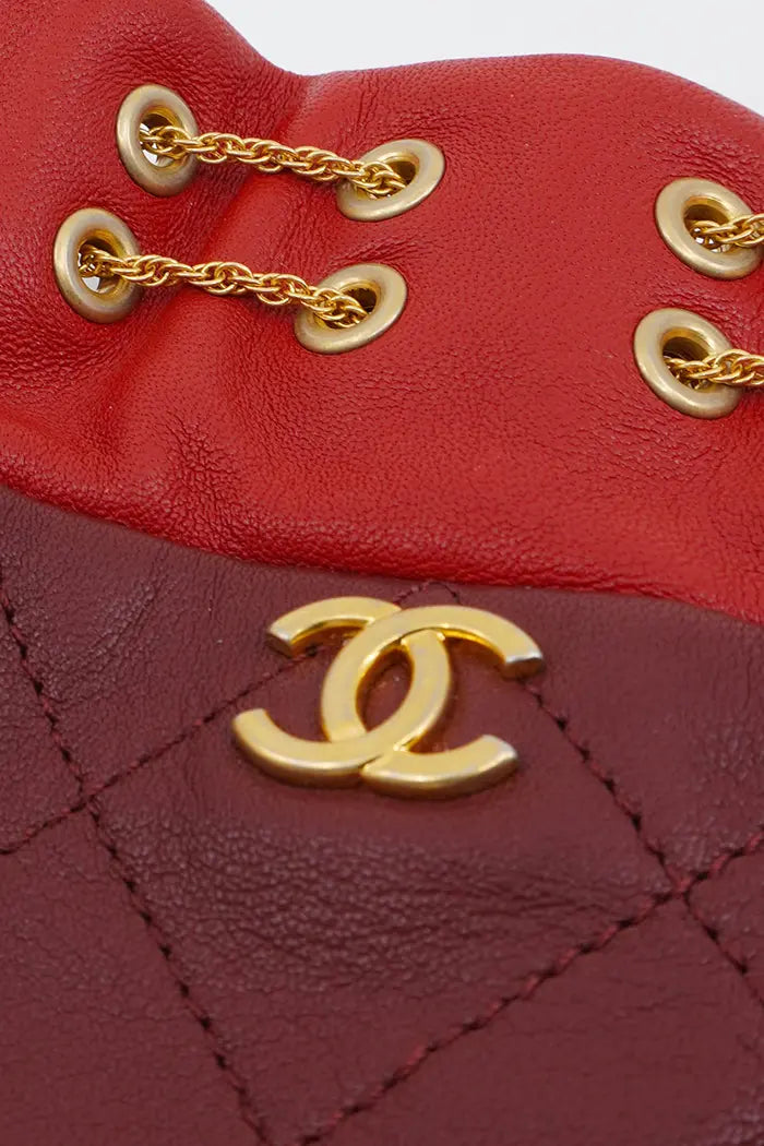 Gros plan sur le logo Chanel, et la double chaine dorée du cordon de serrage du sac Seau de Chanel.