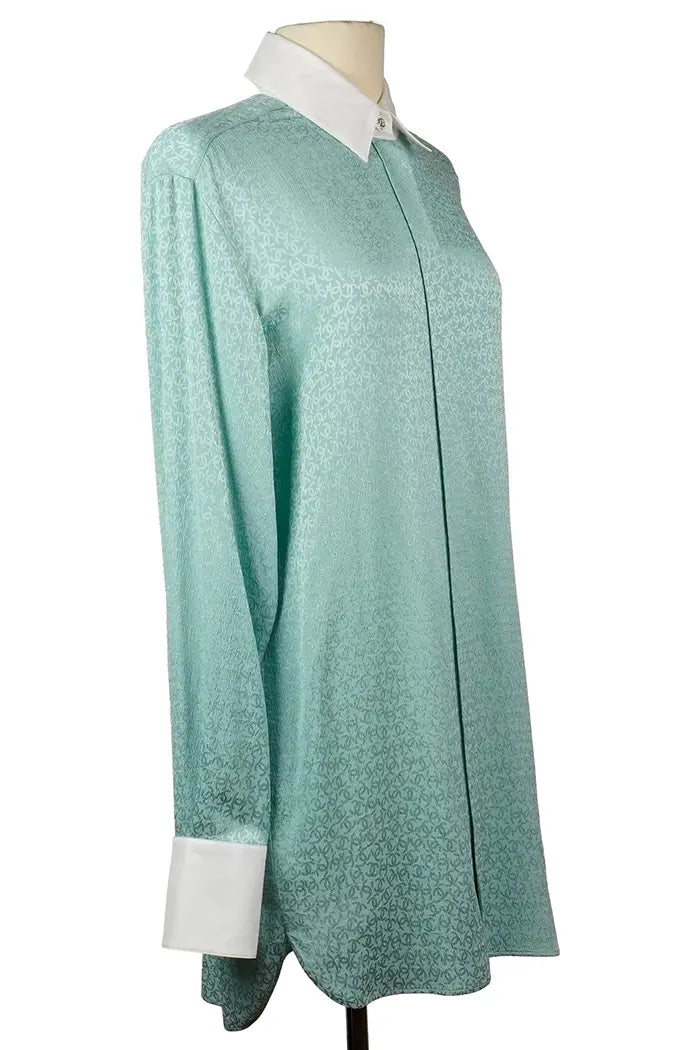Tunique Chanel turquoise portée, col blanc et boutons brillants en détail.