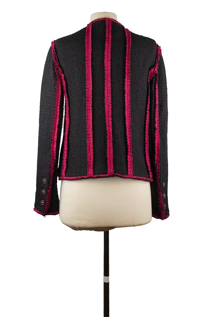 Rückseite der Chanel Jacke aus marineblauem Tweed, gerader Schnitt und kontrastierende Ärmel, sorgfältige Verarbeitung, die typisch für das Haus ist.