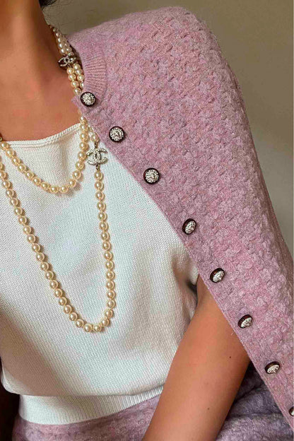 A woman wearing Chanel pink knitted cardigan, with tank top and pearls Chanel. Reference 1000018. Reench, preloved luxe.