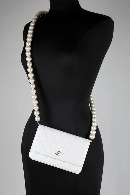 Eine Chanel WOC-Tasche, die von einem Model quer über dem Körper getragen wird und die Länge des mit Perlen besetzten Riemens zeigt.
