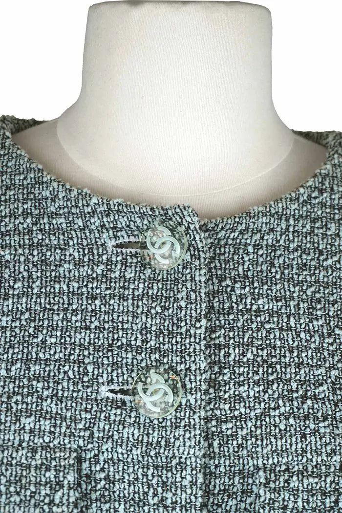 Chaqueta de tweed azul, artículo usado, zoom en el cuello redondo y los botones Chanel con la doble CC entrelazada