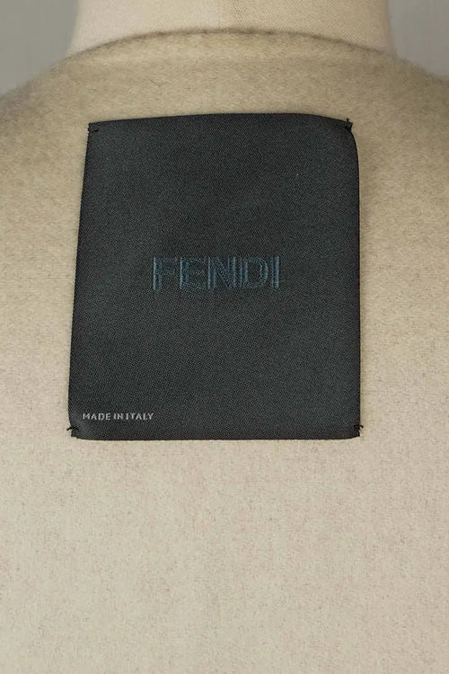 Etiqueta interior Fendi negra bordada con "Made in Italy" sobre fondo de lana marfil.