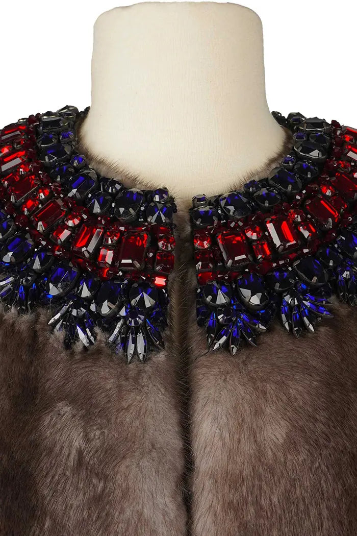 Vue rapprochée du col fermé, révélant la densité des broderies et la finition couture.
