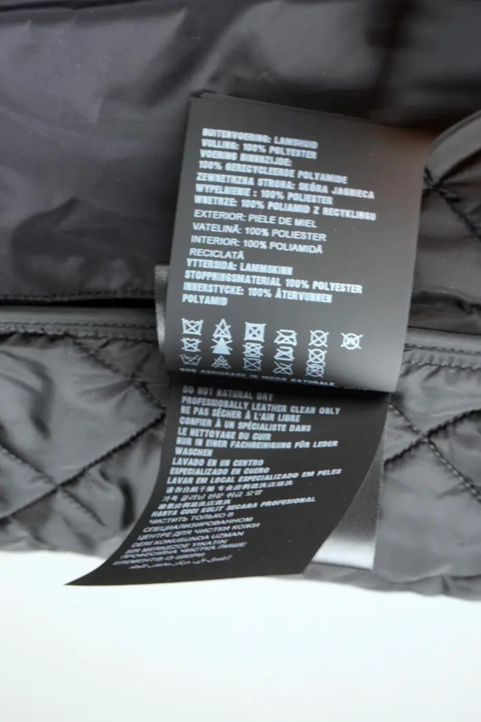 Chaqueta Prada acolchada negra en piel de cordero napa, artículo de segunda mano, zoom en la etiqueta de composición