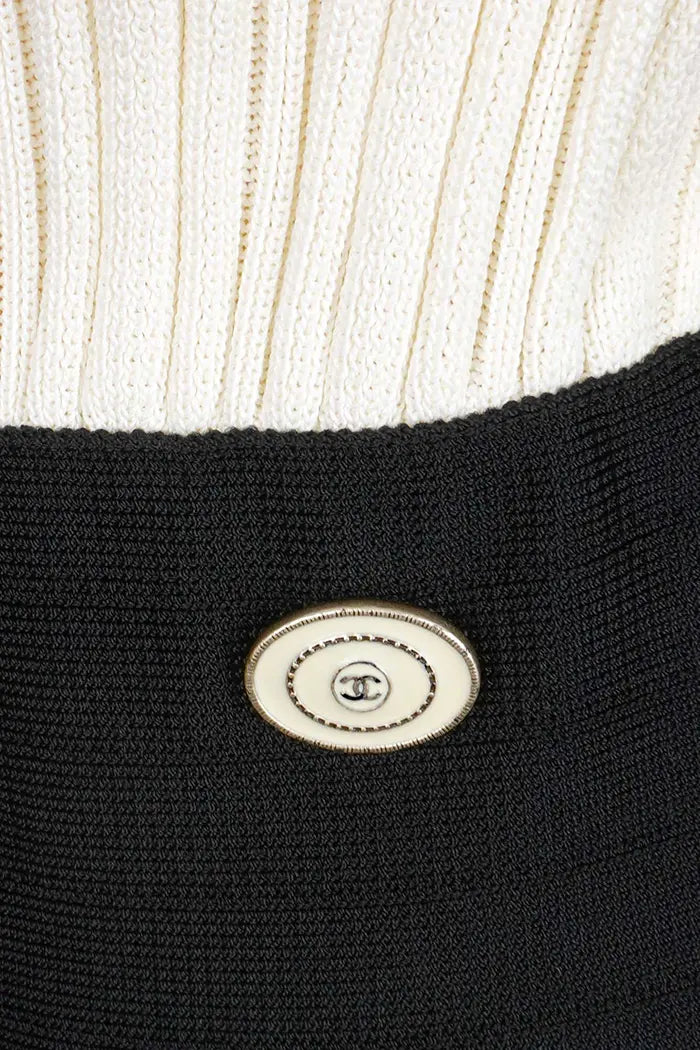 Vestido Chanel color crema con detalles y pajarita negros, artículo seminuevo, zoom sobre el emblemático botón CC