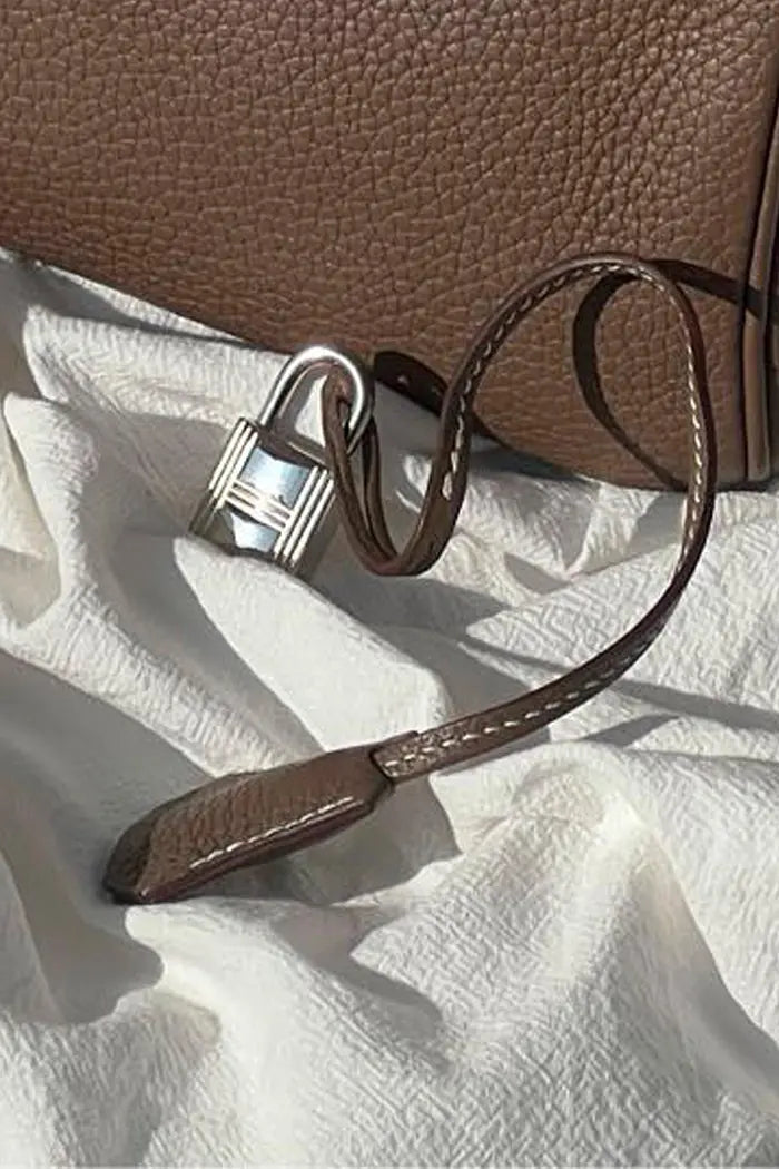Zoom sur la clochette et le cadenas de l'Hermès Birkin 30 d'occasion en couleur Étoupe Retourné en cuir Epsom. Certifié authentique, en très bon état.