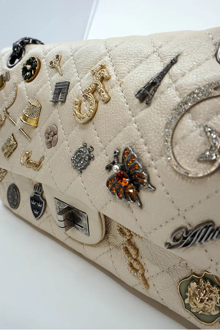 Detalle de los charms del bolso Chanel : camelia, botella N°5, estrella y otros símbolos.