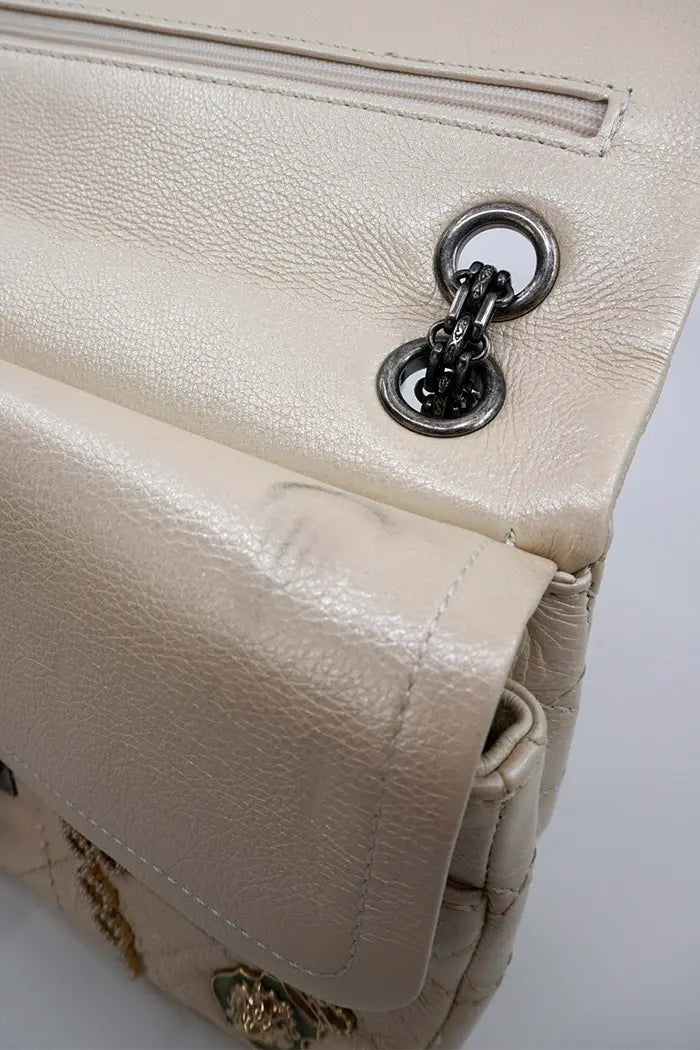 Zoom sobre la cadena de plata envejecida del bolso Chanel y la textura de la piel iridiscente.