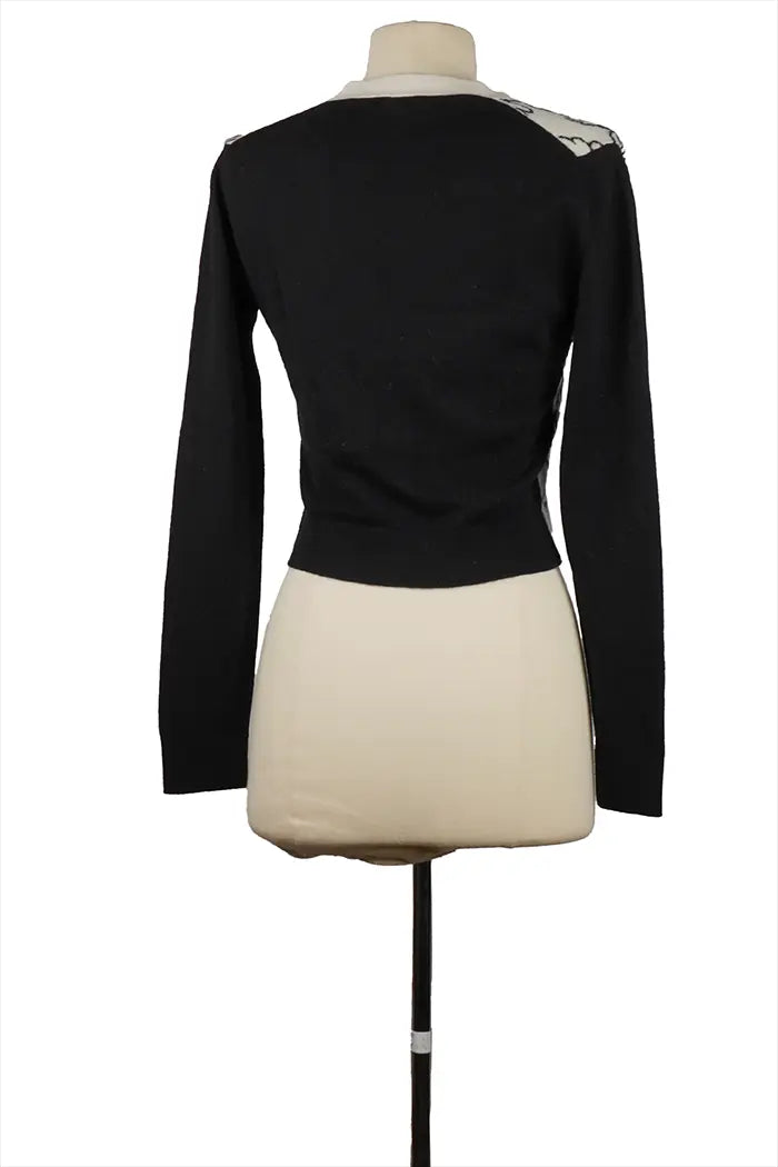 Schwarze Rückseite der Chanel Strickjacke aus Kaschmir am Model, passende Ärmel und gerader Schnitt, schickes zweifarbiges Stück mit ikonischen Couture-Details.