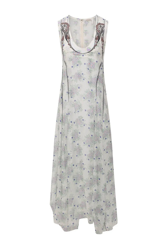 Vestido Chloé de seda blanca en maniquí, estampado floral naïf, bordado a contraste en el escote, corte fluido y largo asimétrico.